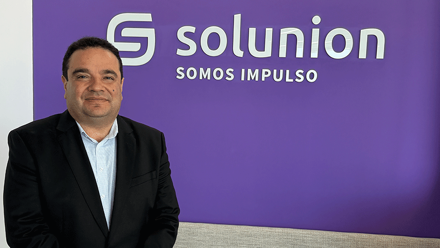 Retrato de Bernardo Barrera, Country Manager de Solunion Perú, delante de una cartel con el logo de la compañía.